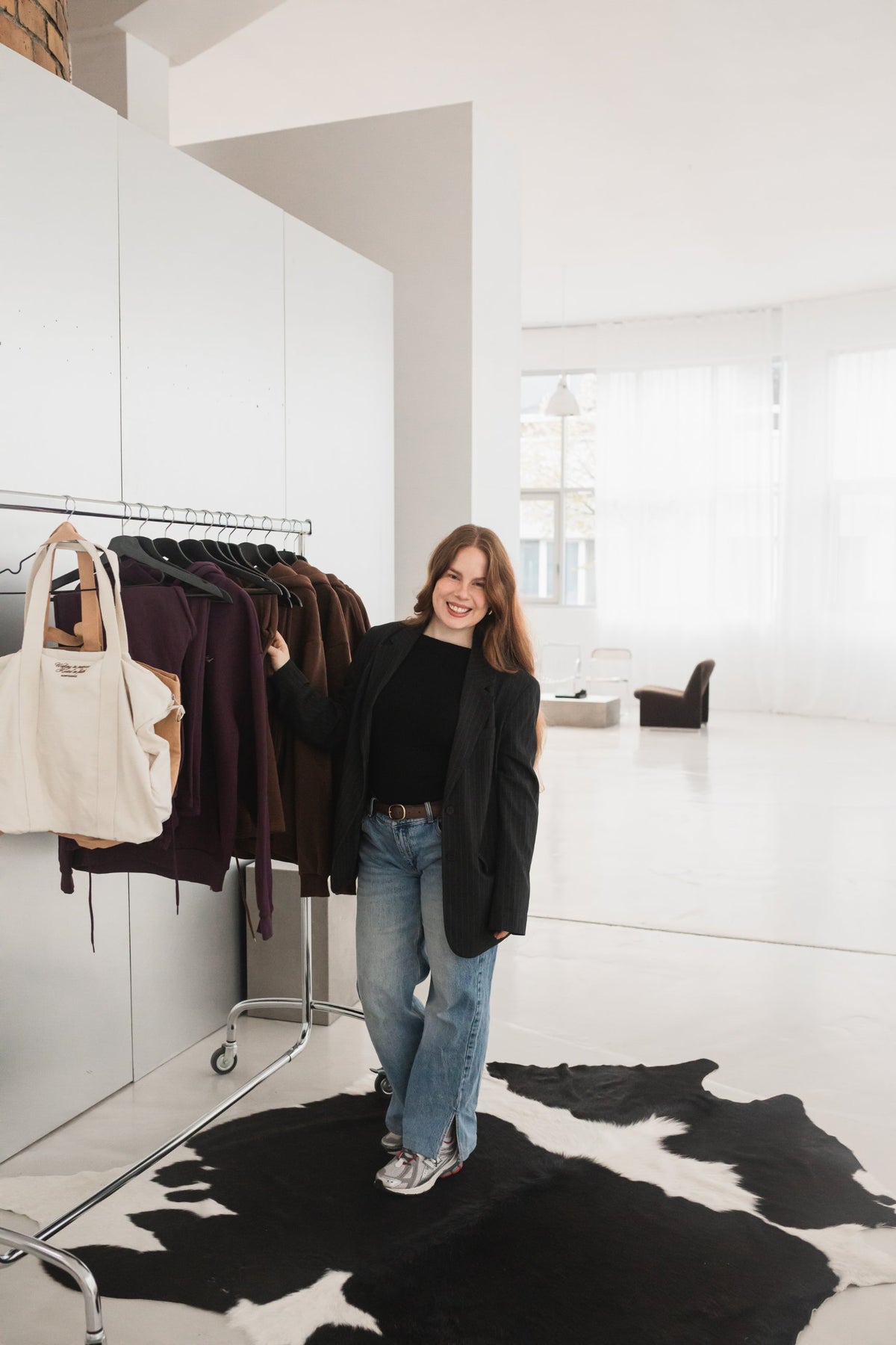 Karina, Gründerin von Godfidence, neben der Kleiderstange mit der Rooted Kollektion